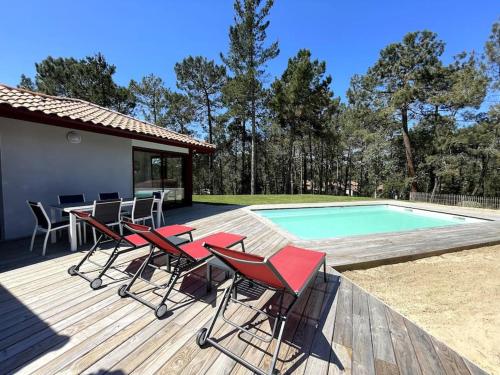 une terrasse avec des chaises rouges et une piscine dans l'établissement Maison 5 personnes avec piscine privée chauffée - Private heated pool 5 people house - Moliets-et-Maa - Landes - France, à Moliets-et-Maa