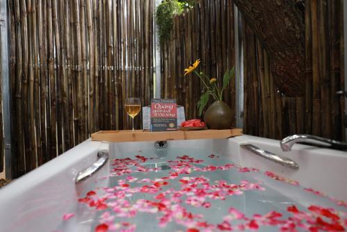 eine Badewanne mit einem Glas Wein und Blumen. in der Unterkunft 6Senses Garden Homestay in Hòa Bình