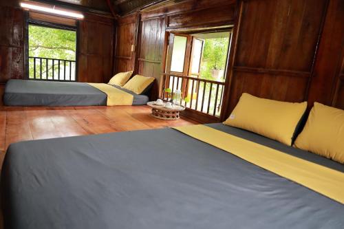 two beds in a room with wooden walls and windows at 6Senses Garden Homestay in Hòa Bình