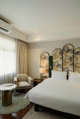 a hotel room with a bed and a chair at The 3sis Hotel in Chiang Mai