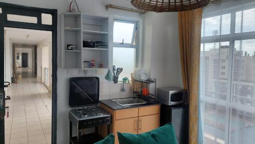 eine Küche mit Spüle, Herd und Fenster in der Unterkunft Cosy Studio with Workspace in Nairobi