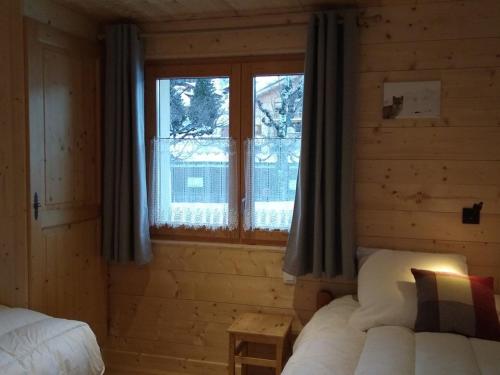 a bedroom with two beds and a window in a log cabin at Appartement 6 pers, 3 ch, centre village, avec WIFI et poêle à granules - FR-1-733-85 in Crest-Voland