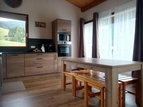 une cuisine avec une table en bois et une grande fenêtre dans l'établissement Duplex 6 pers. avec balcon exposé sud, à 5 min des pistes - Crest-Voland, France - FR-1-733-81, à Crest-Voland