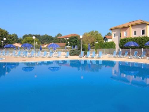 une grande piscine avec chaises et parasols dans l'établissement Appartement avec piscine, tennis et terrasse à Soustons – Idéal famille - FR-1-379-164, à Soustons