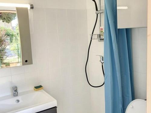 une salle de bain avec une douche avec un rideau de douche bleu dans l'établissement T2 rénové, climatisé au cœur de la Favière avec parking et terrasse/jardinet exposés Sud-Est. - FR-1-610-87, à Bormes-les-Mimosas