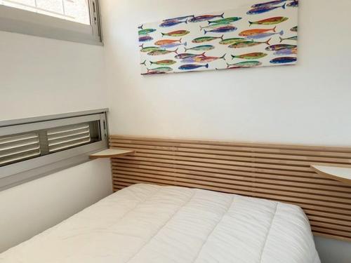 - une chambre avec un lit et une peinture de poissons dans l'établissement T2 rénové, climatisé au cœur de la Favière avec parking et terrasse/jardinet exposés Sud-Est. - FR-1-610-87, à Bormes-les-Mimosas