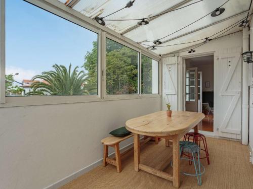 Cette chambre dispose d'une table en bois et de fenêtres. dans l'établissement Spacieux appart 3* à Biarritz, proche commerces, plage et centre, avec wifi et balcon - FR-1-3-589, à Biarritz
