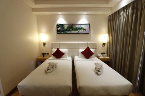 two beds in a hotel room with teddy bears on them at Pearltree Hotels And Resorts in Purulia