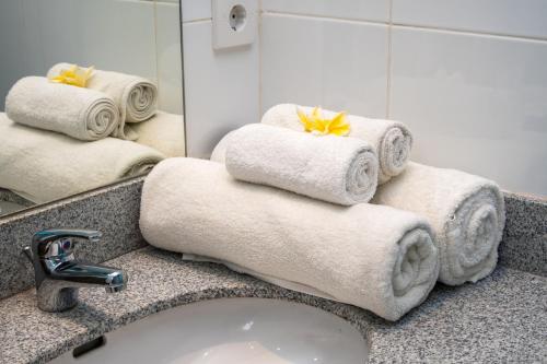 een badkamer met handdoeken, een wastafel en een spiegel bij Graha Wiyata in Tanah Lot