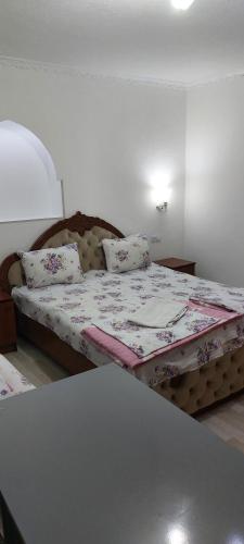 a small bedroom with a bed with a floral bedspread at Hotel Rahmon - 2 in Samarkand