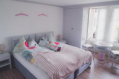 a white bedroom with a bed with pink and white sheets at Dreierzimmer in Därligen