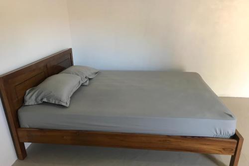 łóżko z drewnianą ramą i poduszką w obiekcie OYO 92603 Lidya Homestay w Labuan Bajo