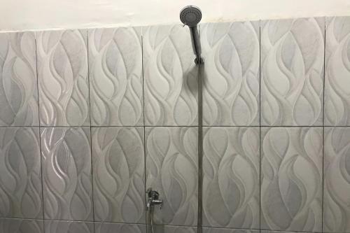 prysznic z głowicą prysznicową na ścianie wyłożonej kafelkami w obiekcie OYO 92603 Lidya Homestay w Labuan Bajo