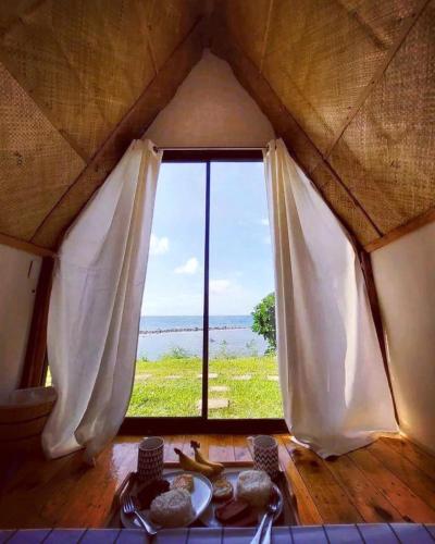 uma janela num quarto com vista para o oceano em Casay Beach Huts by HiveRooms em Dalaguete