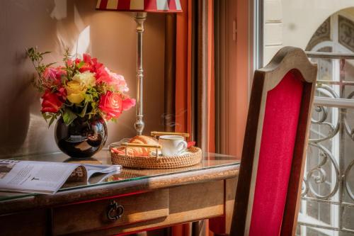 a table with a vase of flowers and a cup of coffee at Hotel Trianon Rive Gauche in Paris