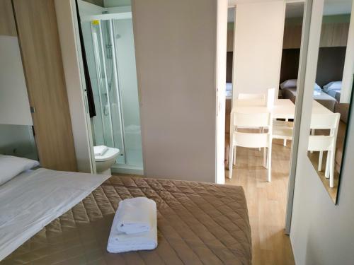 a bedroom with a bed and a dining room with a table at Garda Di Vino Agricamping & Wine Shop Lazise in Ronchi