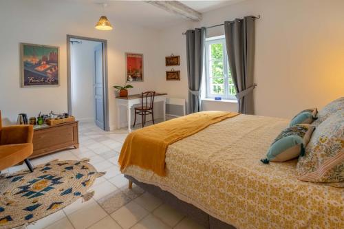 una camera con letto, tavolo e sedia di Maison d'hôtes ÔVillage a Ouveillan
