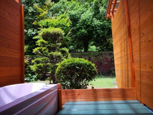 an open door to a garden with a bath tub at ボルダリング＆SPA-安吏樹リゾート修善寺ANNEX- in Izu