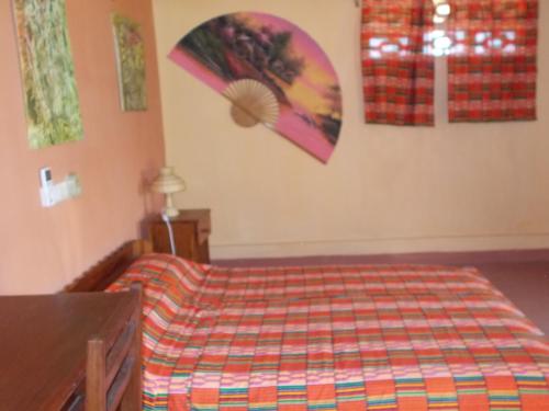 a bedroom with a bed with a colorful comforter at Hôtel Alizé Plage in Baguida