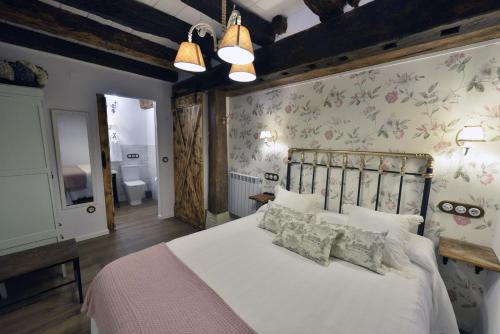 a bedroom with a large white bed with floral wallpaper at Casa Rural El Rotejar in El Royo