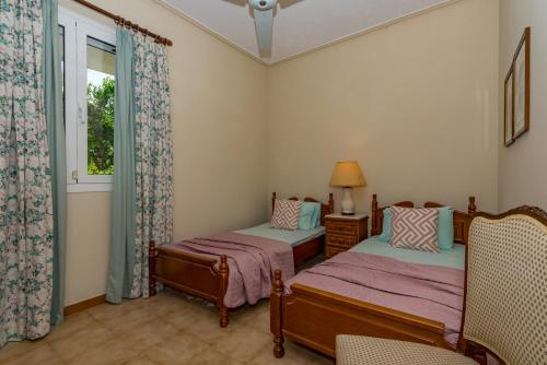 una camera da letto con due letti e una finestra di Yiolanda Pool Villa by "Elite" a Città di Zante