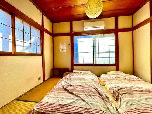 un grande letto in una stanza con due finestre di Wabi Sabi Hostel a Tokyo