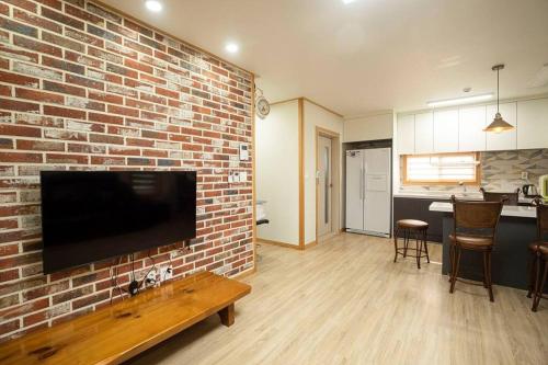 済州市にあるArche House Bのレンガの壁と薄型テレビのあるリビングルーム