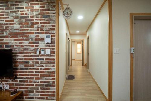 Arche House B في جيجو: ممر ذو جدار من الطوب وساعة معلقة على الحائط