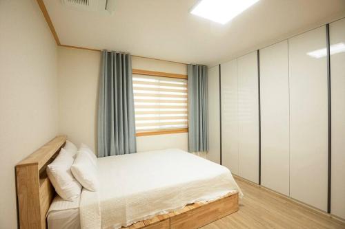 una piccola camera da letto con un letto e una finestra di Arche House B a Jeju