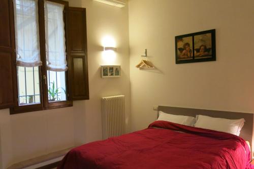 a bedroom with a bed with red sheets and a window at Atelier Della Castellina - SELF CHECK IN in Imola