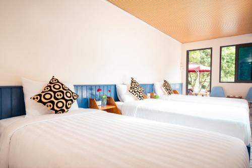 Duas camas brancas num quarto com janelas em Catba Papillon Garden Bungalows & Resort em Ilha de Cát Bà