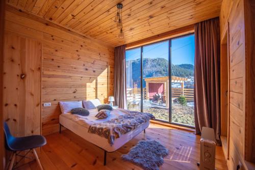 a bedroom with a bed and a large window at Svaneti Сountryside 1 in Shkaleri