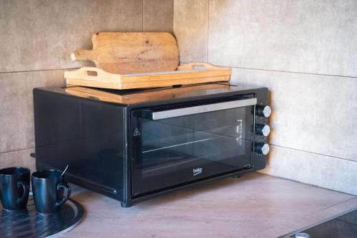 a black microwave with a cutting board on top of it at Ideal six-person villa for large families with pets, featuring barbecue and spacious yard Svaneti Сountryside 1 in Shkaleri