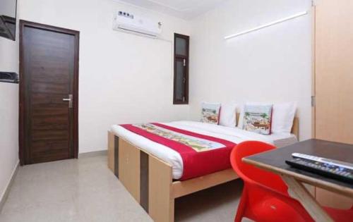 a bedroom with a bed with a desk and a red chair at POP 81169H Sunview Stay in Gurgaon