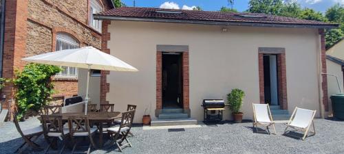 a patio with a table and chairs and an umbrella at Gîte familial de la Bastide du puech in Cransac