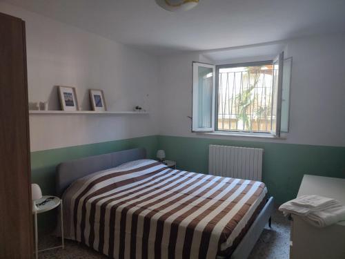 a bedroom with a bed with a striped blanket and a window at Casa Venezia in Senigallia