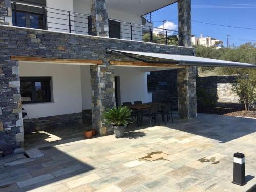 a stone house with a patio with a table at Luxury Villa by the Sea in Volos