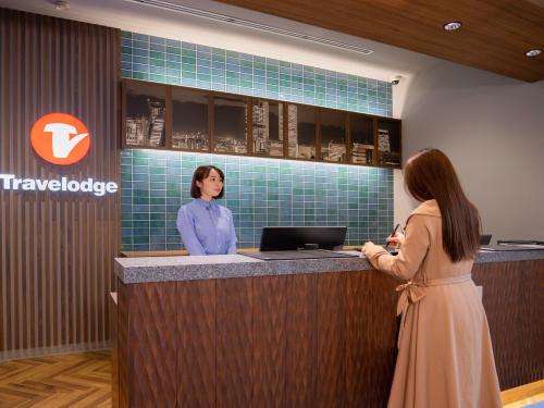 two women standing at a reception counter in a travelodge at Travelodge Nagoya Sakae in Nagoya