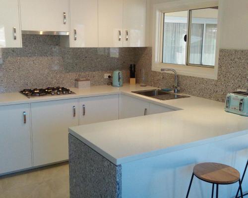 a kitchen with white cabinets and a sink at Eagles Nest - Ardrossan in Ardrossan