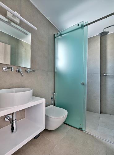 a bathroom with a shower and a toilet and a sink at Bedspot Apartments Paros in Naousa