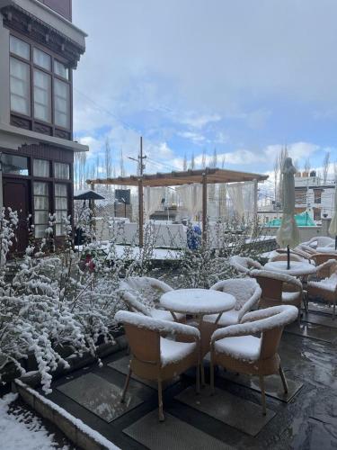 a patio with tables and chairs covered in snow at Ashoka Ladakh in Leh