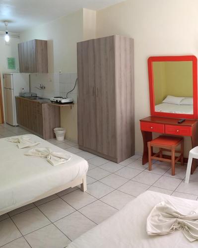 a bedroom with two beds and a red dresser and a mirror at Rooms Anastasia Paralia in Paralia Katerinis