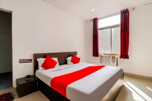 een slaapkamer met een groot bed met rode kussens bij OYO Flagship 80902 Swagat Hotel in Bhiwadi
