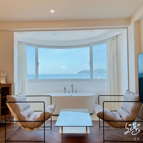 a living room with two chairs and a bath tub at Stay Saeroc in Geoje 