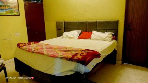 een slaapkamer met een bed met witte lakens en rode kussens bij OYO S.R. Hotel in Meerut