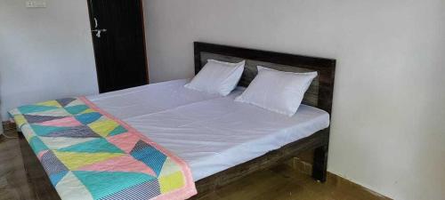 een bed met een kleurrijke deken en kussens erop bij OYO Hotel Daisy in Jabalpur