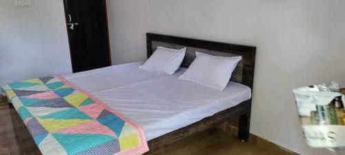 een bed met witte kussens en een kleurrijke deken erop bij OYO Hotel Daisy in Jabalpur