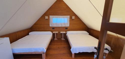 a attic room with two beds and a window at Boho Glamping in Cádiz