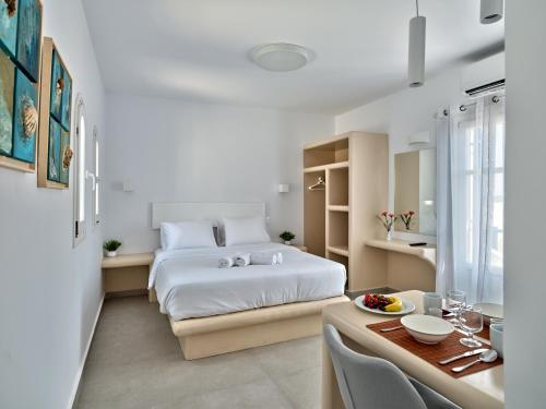 a white bedroom with a bed and a table with a dining room at Bedspot Apartments Paros in Naousa