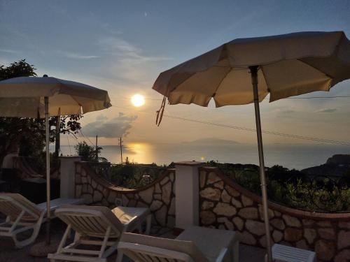 een patio met stoelen en parasols en uitzicht op de zonsondergang bij Casa Astra in Anacapri